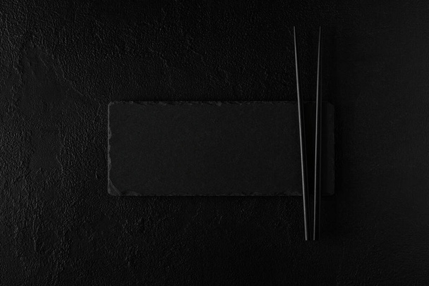 Empty black slate plate with chopstick on dark Background. Flat Lay. Top view. Mock-up - Fotografie, Obrázek