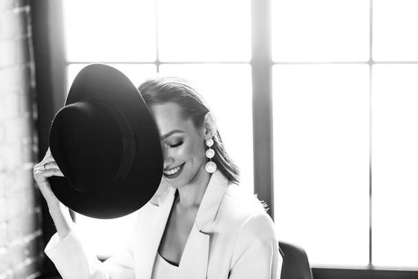 Mladá dívka v bílém obleku a s černým kloboukem. Koncept oděvu. - Fotografie, Obrázek