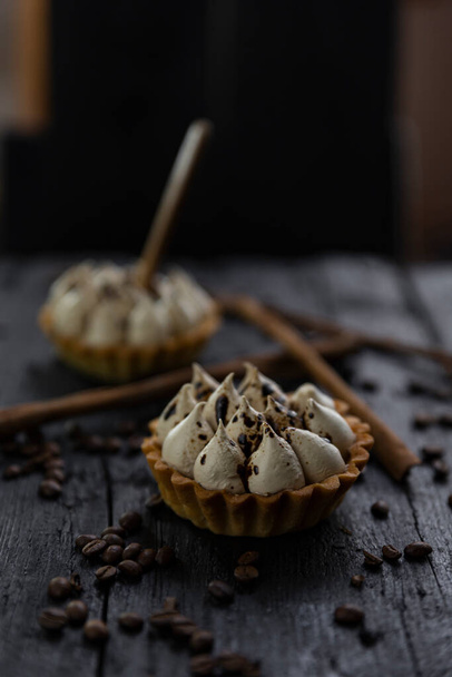 Cappuccino tart with cinnamon sticks and coffee beans on rustic wooden table  - Valokuva, kuva