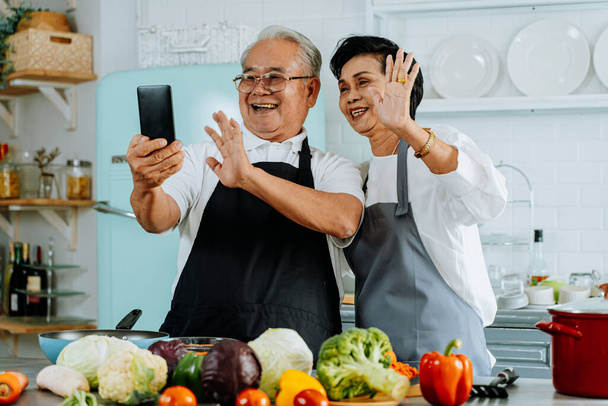 Happy senior Asian couple making video call in kitchen - Foto, immagini