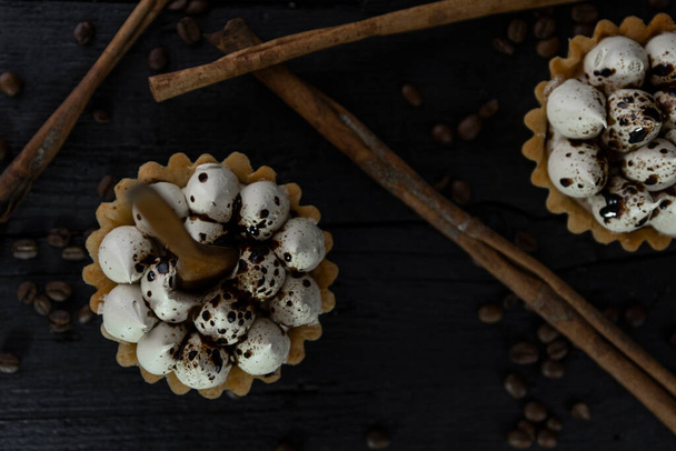 Cappuccino tart with cinnamon sticks and coffee beans on rustic wooden table  - Фото, изображение