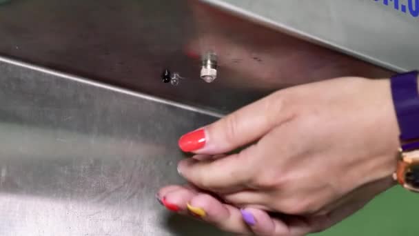Een vrouw behandelt haar handen met een ontsmettingsmiddel. Vrouwenhanden gebruiken een contactloze desinfector. - Video
