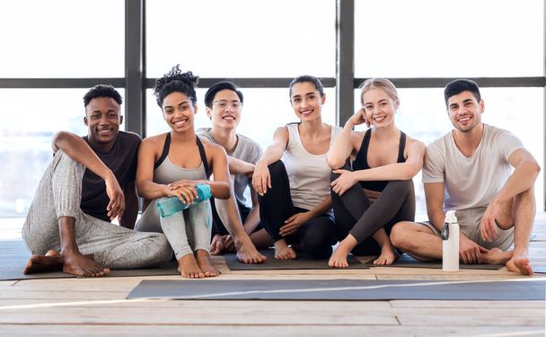 Retrato de personas multiétnicas sonrientes posando en colchonetas después del yoga en el estudio
 - Foto, imagen