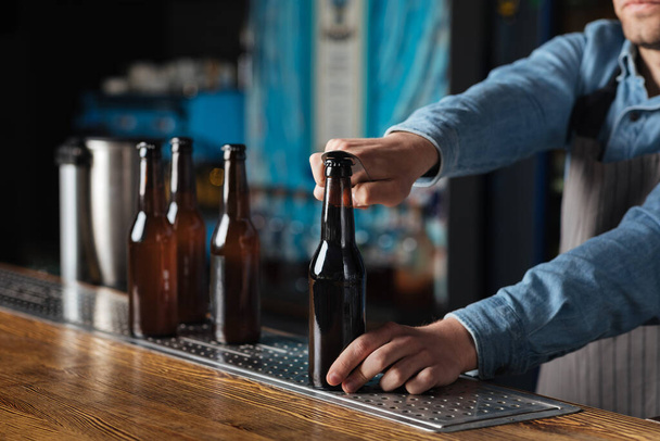 Leisure, friends company and pub. Bartender opens bottle of beer - Foto, Imagem
