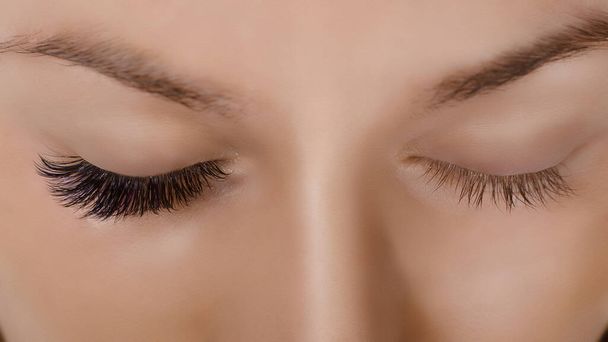 Eyelash Extension Procedure. Close up view of beautiful female eye with long eyelashes, smooth healthy skin. - Fotoğraf, Görsel