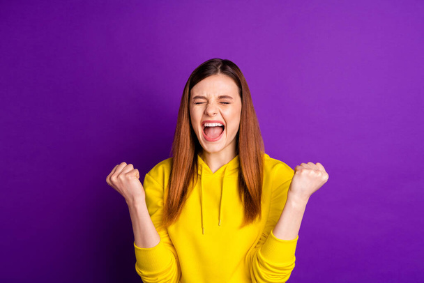 Photo of attractive crazy lady celebrating amazing achievement raise fists rejoicing screaming wear casual bright yellow hoodie sweatshirt isolated violet color background - Фото, зображення