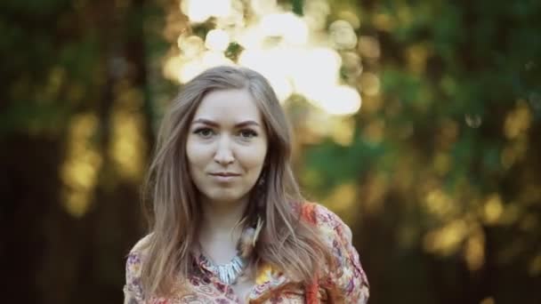 Beautiful young woman wearing bohostyle clothes posing in the rays of the evening sun, sunset. Boho style fashion, female wearing silver jewelry having fun in park outdoors. - Materiaali, video