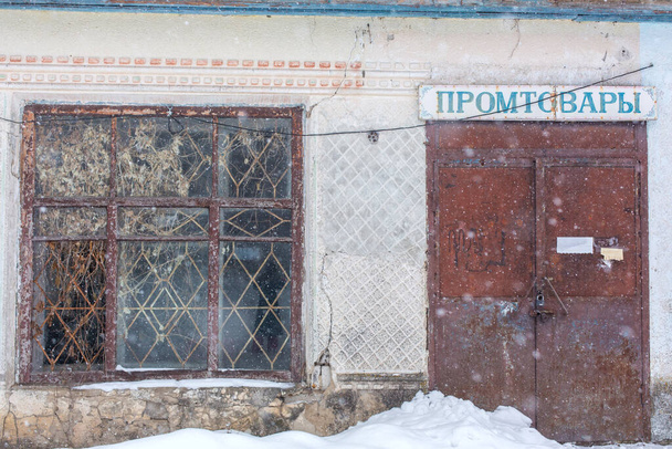 Abandoned old building with bars on the windows. Winter it's snowing. - Фото, изображение