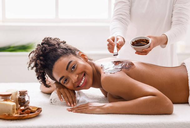 Vrolijk zwart meisje genieten van spa procedures in salon - Foto, afbeelding