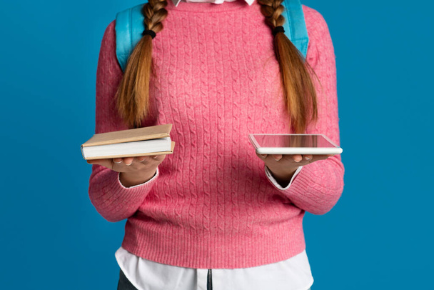 Modern gadget and book. Teen girl holds book and digital tablet in hands - Photo, Image