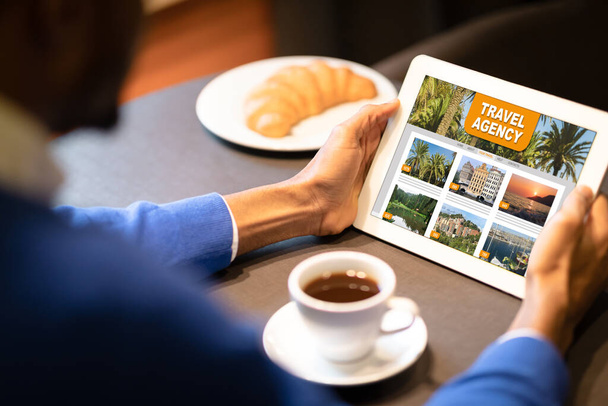 Uomo nero utilizzando Online Travel Agency sito web su Digital Tablet In Cafe - Foto, immagini
