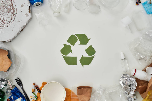 Flatlay composition with different waste, garbage types and recycling sign made of paper in the center over white background - Photo, image