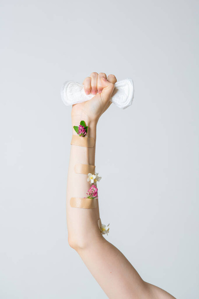 Womans fist as symbol of feminism with menstrual pad and flowers, concept photography for feminist blog or poster - Photo, image