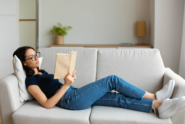 Student Girl Reading Book Studying Lying On Couch At Home - Foto, immagini