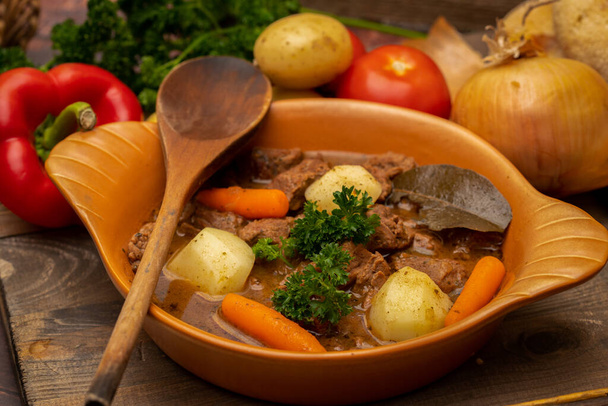 Beef goulash stewed with potatoes, carrots and spices in ceramic pot - Photo, Image