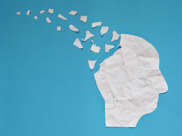 Symbol der Gehirnstörung, dargestellt durch den menschlichen Kopf aus zerknülltem Papier, das auf blauem Hintergrund mit Kopierraum zerrissen wurde. Kreative Idee für Alzheimer, Demenz, Gedächtnisverlust und psychische Gesundheit. - Foto, Bild