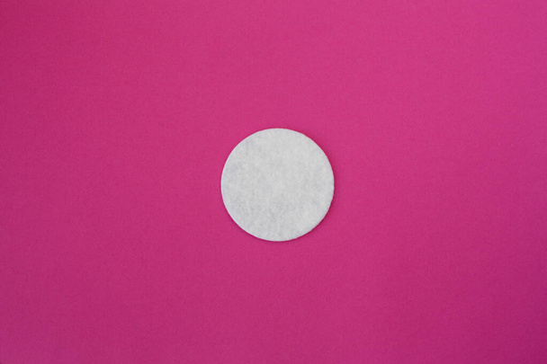 top view on white round cotton disks laid out on a pink background. - 写真・画像