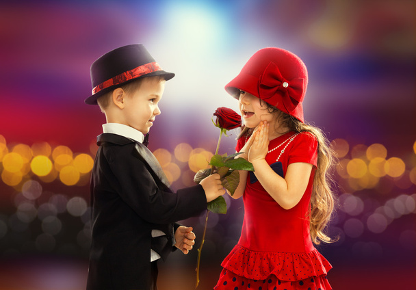 schöner kleiner Junge gibt Mädchen eine Rose - Foto, Bild
