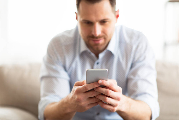 Handsome adult man using smartphone at home - Photo, Image