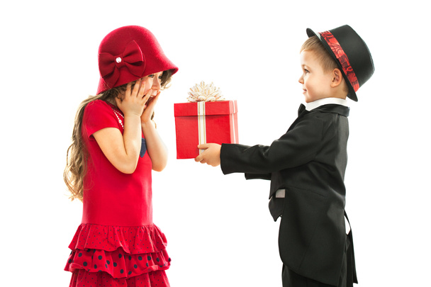 Маленький хлопчик дарує дівчинці подарунок і його збуджений
 - Фото, зображення