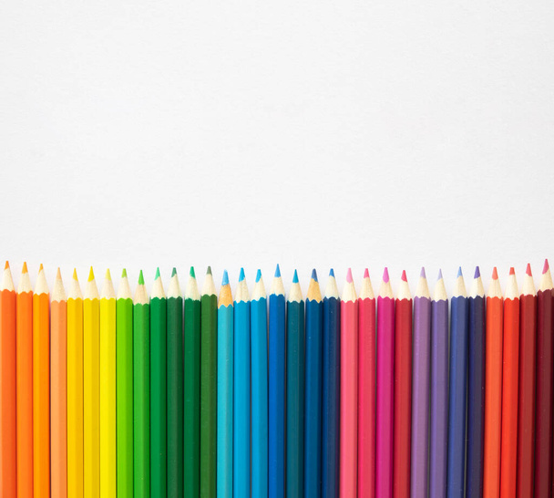 Het concept van de kleuterschool. Bovenaanzicht rand frame gemaakt van gekleurde potloden op een witte achtergrond met kopieerruimte. Vlakke plaat - Foto, afbeelding