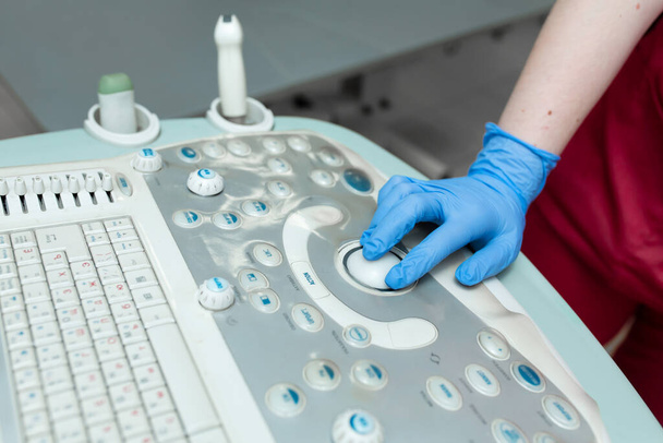 Female doctor's hand on ultrasound machine close up. - Photo, Image