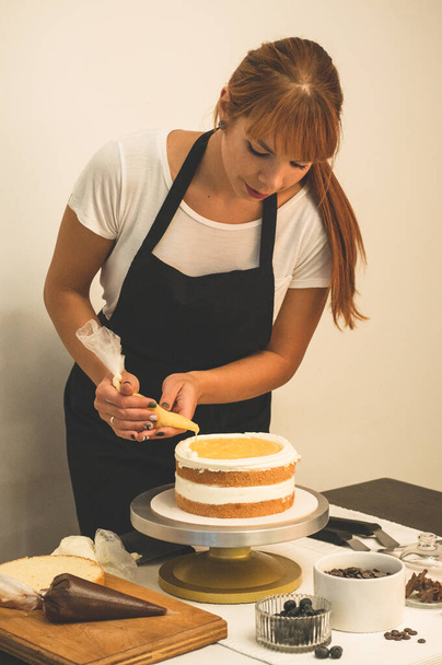 Confectioner girl is preparing a cake. The concept of pastry, cooking cakes - Zdjęcie, obraz