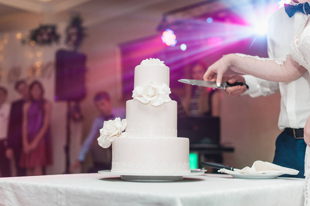 cerimónia de casamento. a noiva eo noivo fazer o seu primeiro caso juntos, cortar o bolo de casamento lindo decorado com flor
 - Foto, Imagem
