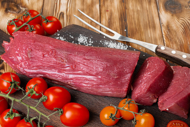 Slices raw meat fillet on wooden board - Foto, afbeelding