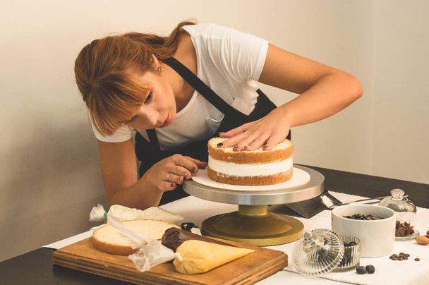 Makeistyttö valmistaa kakkua. Käsite leivonnaiset, ruoanlaitto kakut - Valokuva, kuva