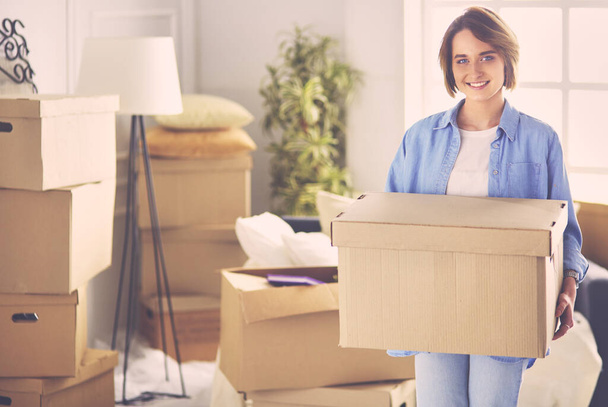 Portrait of pretty woman holding a box at new home - Foto, Imagen