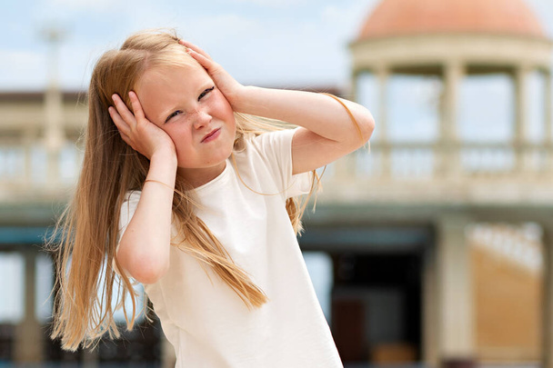 Emociones. Retrato de una niña mostrando su frustración y descontento. En el fondo hay un edificio con una cúpula
. - Foto, imagen