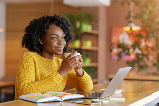 Hayalperest Afrikalı kız internette iş ararken çay içiyor. - Fotoğraf, Görsel