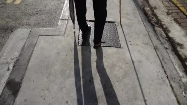 Vista posteriore di una donna disabile camminare con bastone di sostegno e ombrello in strada. - Filmati, video