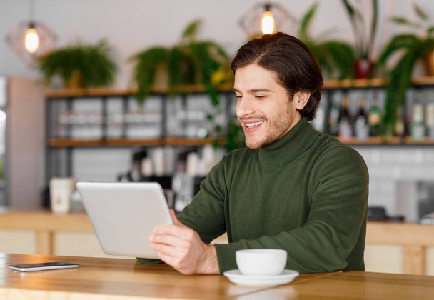 Fröhlicher Typ probiert neue Business-App aus und sitzt im Café - Foto, Bild