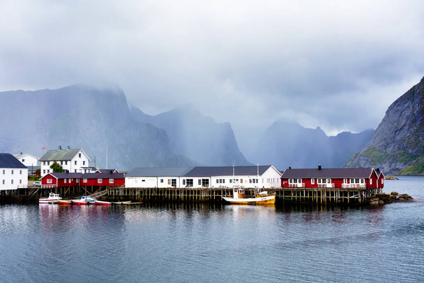 Słynna atrakcja turystyczna Wioska rybacka Hamnoy na Wyspach Lofoten, Norwegia z czerwonymi i żółtymi domami rorbu. Spokojna, rozmazana woda - Zdjęcie, obraz