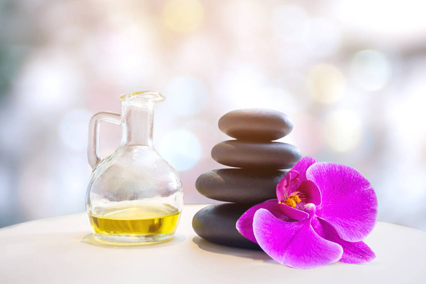 bottle of aroma essential oil with candle and flower on stone table, spa concept. - Foto, Imagem