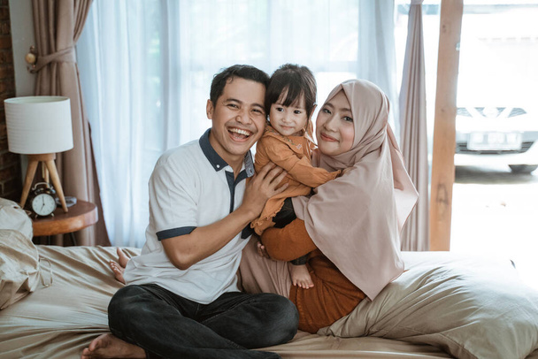 Muslim families smile happily when hugging while sitting on the bed - Foto, Imagem