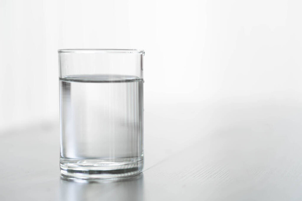 Glass of water on wood table with light in the morning, healthy care concept, selective focus - Photo, image