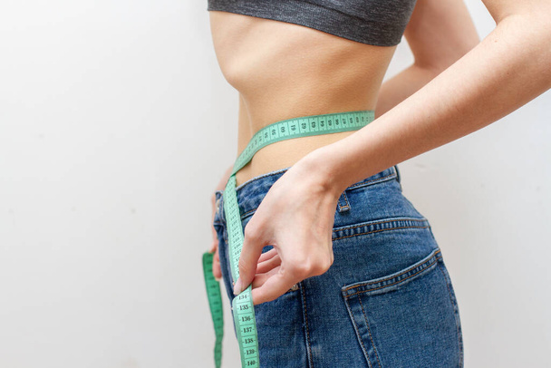 Woman is measuring waist after weight loss. Diet concept. - Foto, afbeelding