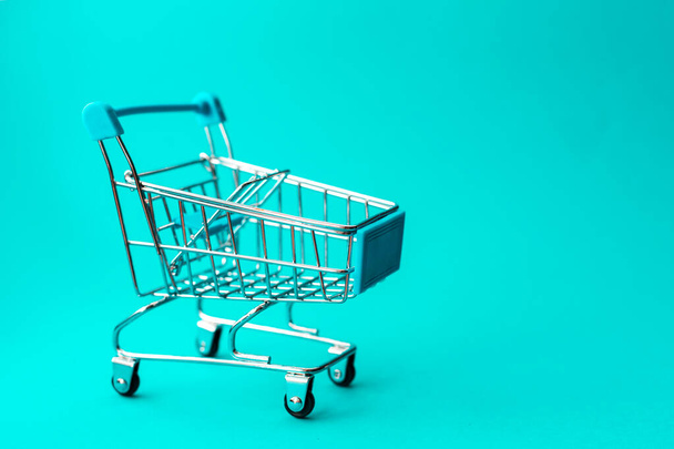 empty metal shopping trolley on green background. Discount and shopping concept. - Foto, Imagem