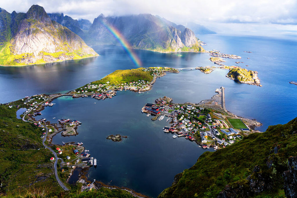 Vista panorámica aérea soleada de las impresionantes montañas y el pueblo de Reine en las islas Lofoten, Noruega desde la cresta de Reinebringen. Vista panorámica con un arco iris y picos rugosos
. - Foto, Imagen