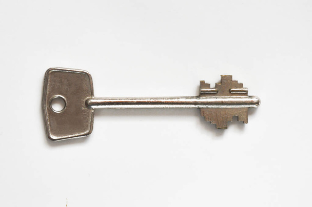 το κλειδί της εξώπορτας. μεταλλικό κλειδί σε λευκό φόντο. - Φωτογραφία, εικόνα