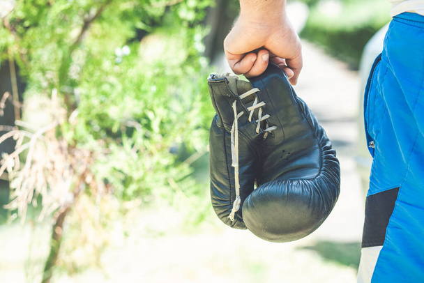 hand houdt zwart bokshandschoenen geïsoleerd op natuur achtergrond - Foto, afbeelding