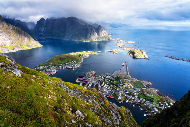 Slunečný vzdušný panoramatický výhled na ohromující hory a vesnici Reine na ostrovech Lofoten, Norsko z hřebene Reinebringen. Scénická vyhlídka s duhou a drsnými štíty. - Fotografie, Obrázek