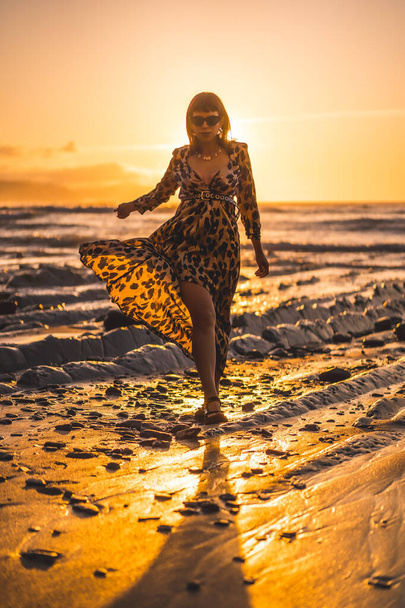 Young woman in leopard dress by the sea at sunset. - Foto, immagini