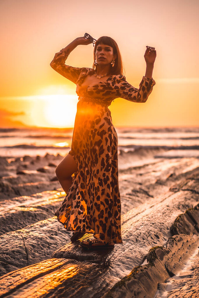 Young woman in leopard dress by the sea at sunset. - Fotó, kép