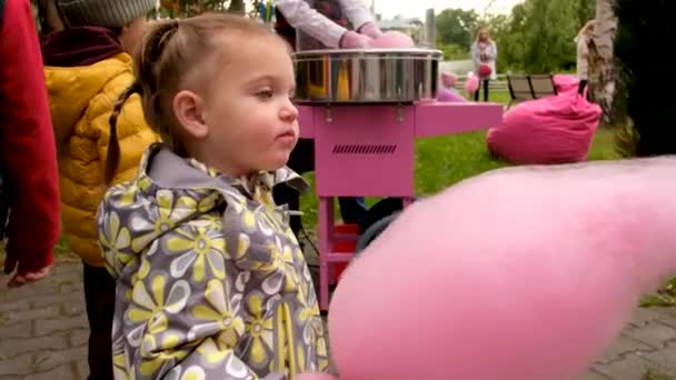 Dziewczyna je nici cukierkowe w parku - Materiał filmowy, wideo