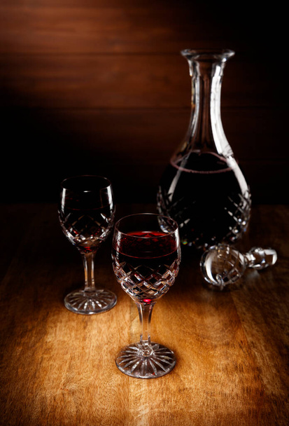 Spotlight na 2 sklenice portského a karafa na starožitném dřevěném stole. - Fotografie, Obrázek