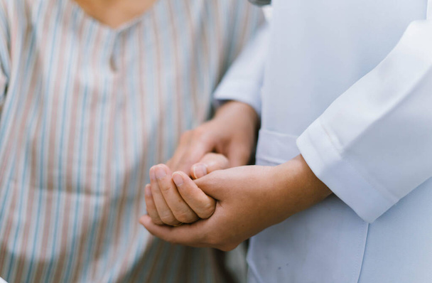 zblízka lékař držet za ruku seniora pacienta, lékařská zodpovědnost - Fotografie, Obrázek